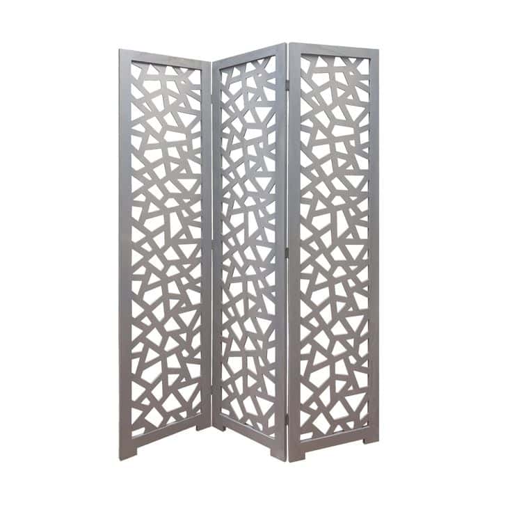 Folding decorative room divider with geometric cutout design in white material.
